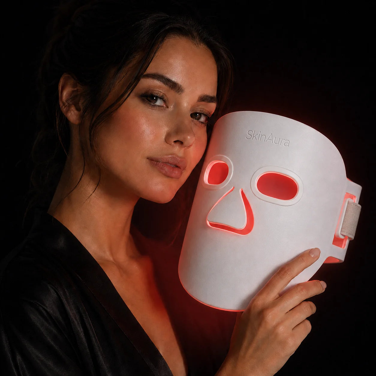 A woman holding The Aura™ light-therapy mask